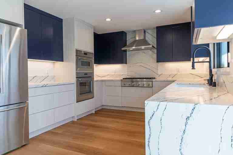 Modern kitchen with white and navy cabinetry, marble countertops, and stainless steel appliances Anaheim, CA.