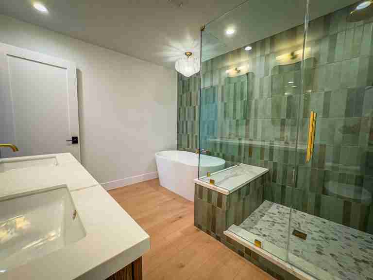 Bathroom remodeling featuring green tiled shower and elegant bathtub in Huntington Beach, CA.