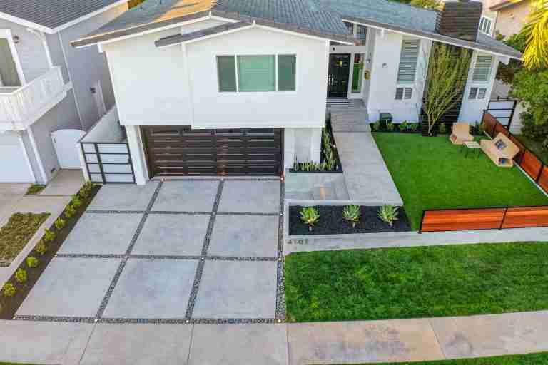 White house with a spacious concrete driveway and landscaped front yard. Huntington Beach CA