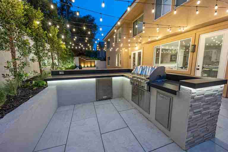 Outdoor kitchen with built-in grill, countertops, and ambient string lighting. Fountain Valley CA