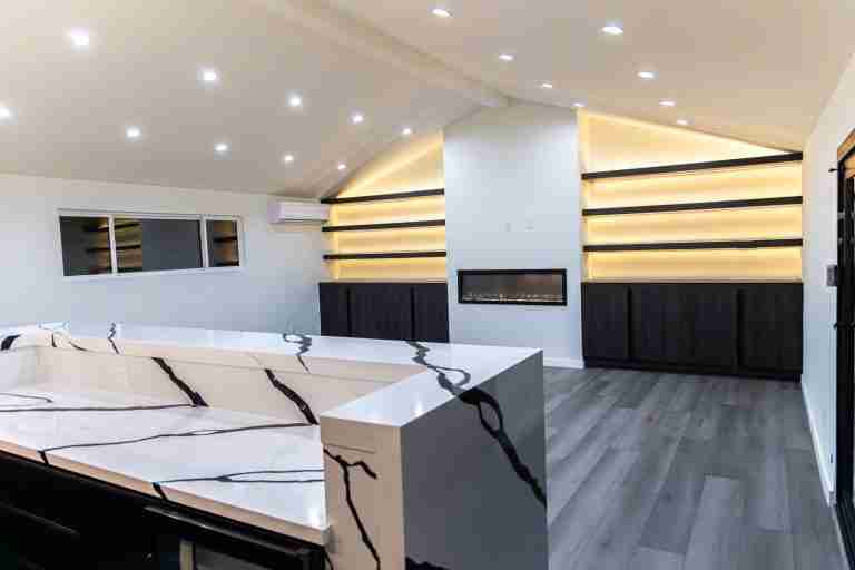 Modern living room featuring a sleek fireplace and custom built-in shelves with ambient lighting in Fullerton CA