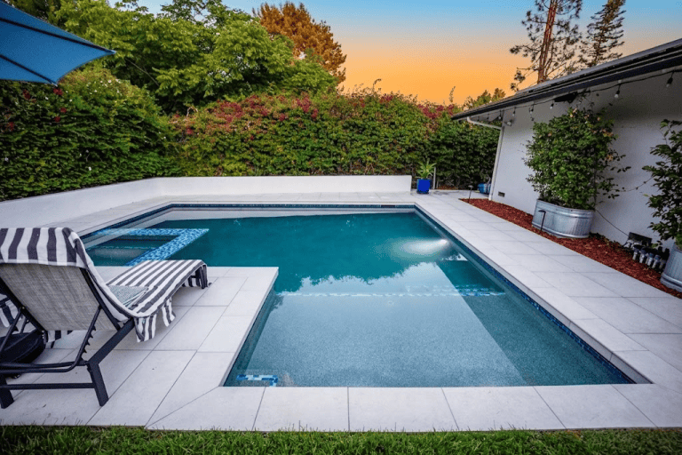 Swimming pool with lounge chairs in a peaceful backyard setting.