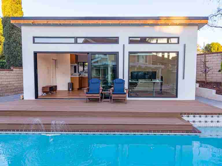 ADU in orange ca Contemporary pool house featuring expansive glass doors, a wooden deck, and outdoor seating in Orange CA