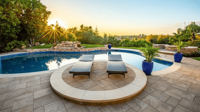 Beautiful backyard pool with two sun loungers and potted plants at sunset. Buena Park, CA