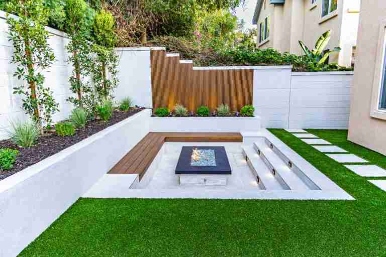 Contemporary backyard patio with built-in seating, fire pit, and lush landscaping. Laguna Niguel CA